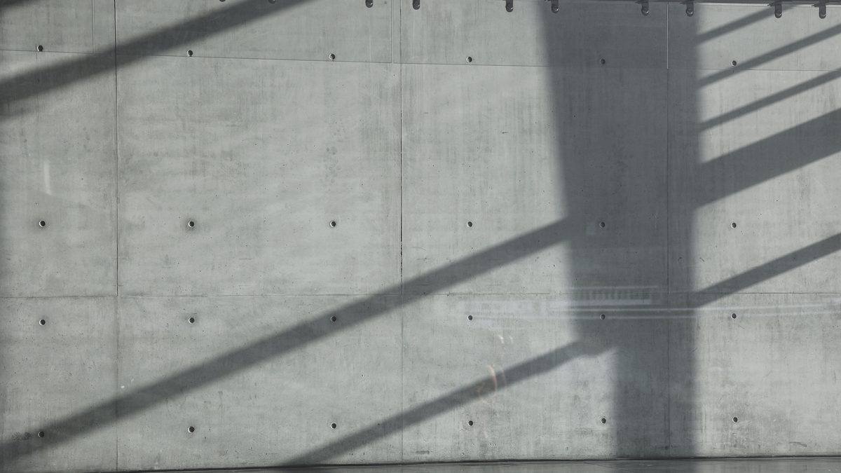Lange schaduwen van een trapleuning over een betonnen wand